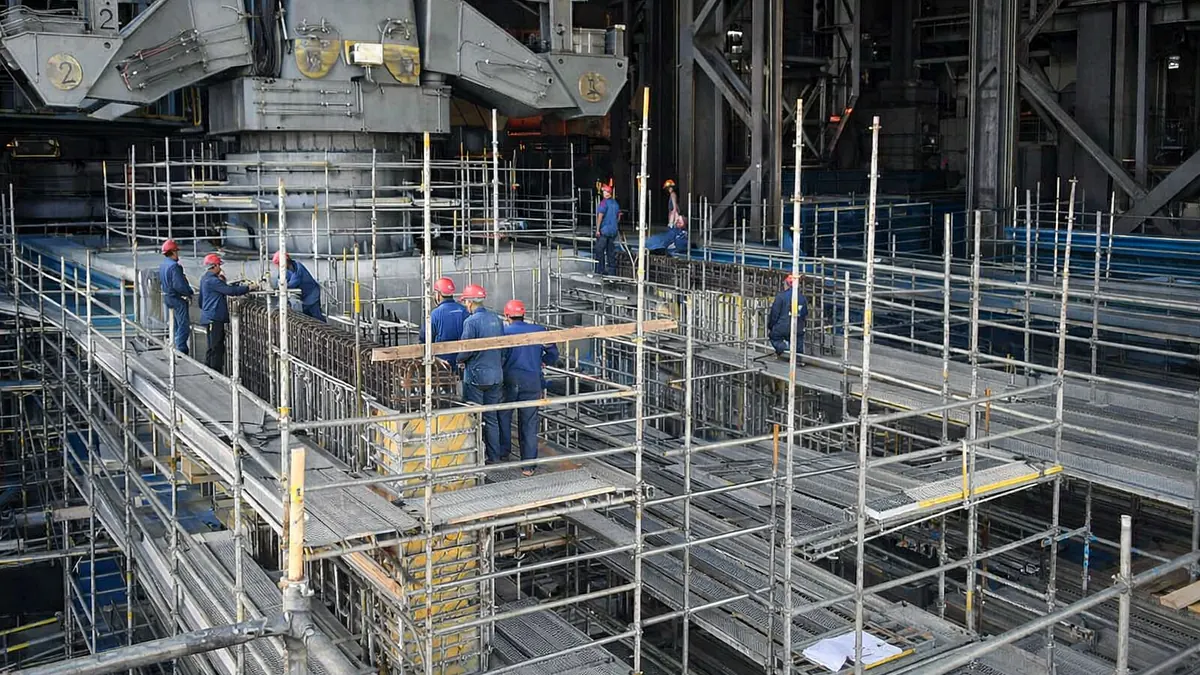 Trabajadores sobre una plataforma de andamio en una instalación industrial.