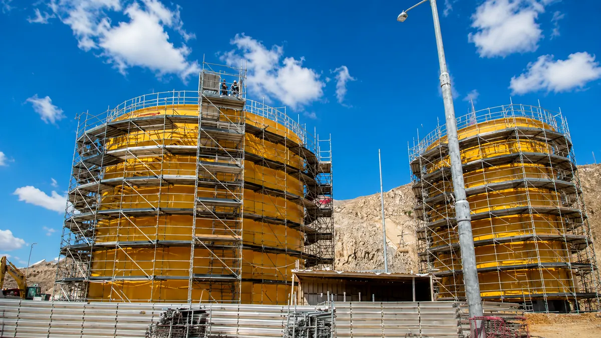 Andamios instalados alrededor de estructuras cilíndricas en un entorno industrial.